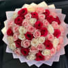 Bouquet of red, pink, and white roses wrapped in pale pink paper