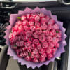 Large bouquet of pink roses wrapped in lavender paper