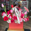 Pink and red flower arrangement in a red gift box with a ribbon handle