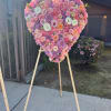 Heart-shaped floral arrangement on a wooden easel with pink and purple blooms