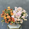 Mixed bouquet of orange, pink, and cream flowers in a ceramic vase