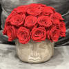 Red roses arranged in a face-shaped stone planter