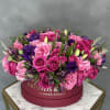 Pink and purple roses arranged in a round hat box