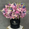 Large bouquet of pink and lavender roses with blue flowers in a black hat box