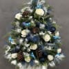 Christmas tree arrangement with white roses, pinecones, and blue ornaments