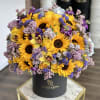 Bouquet of sunflowers, yellow roses, and purple flowers in a black hat box
