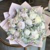 Bouquet of pale peonies and small lavender flowers wrapped in pink paper