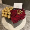 Heart-shaped box of red roses and gold-wrapped chocolates with a card.