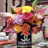 Colorful bouquet of roses, lilies, and daisies in a black Chanel vase
