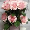 Pink roses arranged in a square glass vase with dark green leaves