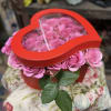 Pink roses in a red heart-shaped box with a clear lid