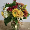 Mixed bouquet with roses, sunflowers, and chrysanthemums in a glass vase