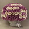Round arrangement of pink and cream roses in a gray vase