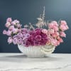 Pink and lavender roses arranged in a white vase