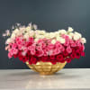 Large arrangement of pink, red, and white roses in a gold vase