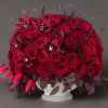 Red rose arrangement with dark orchids in a white pedestal vase