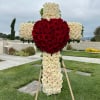 Large cross-shaped floral tribute made of red and white roses on an easel.