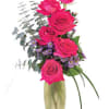 Pink roses arranged in a tall glass vase with purple filler flowers