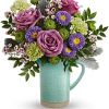 Purple roses and mixed flowers in a turquoise pitcher vase