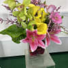 Mixed bouquet of pink and yellow flowers in a clear glass vase