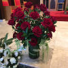 Red roses arranged in a glass vase with trailing greenery