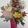 Birthday bouquet with roses, lilies, and a balloon in a pink vase