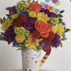 Colorful bouquet in a party cup with balloons and a "CELEBRA EL" topper