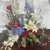 Funeral urn surrounded by red, white, and blue flowers