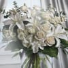 White lilies and cream roses in a bouquet with greenery
