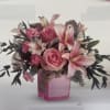 Pink roses and lilies arranged in a pink glass vase