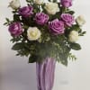 Bouquet of purple and white roses in a tall purple vase