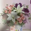 Pink roses, white lilies, and purple flowers in a decorated vase