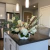 Large white floral arrangement in a marble-look bowl on a kitchen island