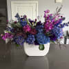 Large blue and purple floral arrangement in a white vase