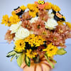 Bouquet of yellow and peach flowers in a pumpkin vase with owl picks