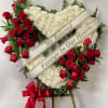 Heart-shaped funeral wreath with red roses and white carnations on an easel