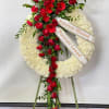 White funeral wreath with red roses and gerbera daisies on an easel