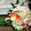 Bouquet of peach and pink roses with pale green hydrangeas