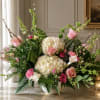 Large floral arrangement with pink roses, white hydrangeas, and calla lilies in a vase