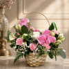 Pink roses and carnations arranged in a wicker basket with a handle