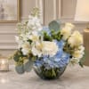 Blue and white flower arrangement in a glass bowl vase