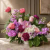 Pink and purple mixed flower arrangement in a white vase