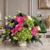 Pink roses and green hydrangeas in a white vase with purple accents