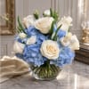 White roses and blue hydrangeas arranged in a clear glass bowl vase