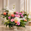 Mixed pink, white, and peach flowers arranged in a white pedestal vase