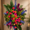 Colorful standing floral arrangement with roses, gerberas, carnations, and blue spikes