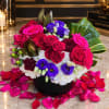 Mixed bouquet of red and pink roses with purple blooms in a black vase