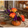 Orange and purple floral arrangement in a pumpkin-shaped container