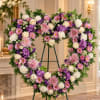 Heart-shaped floral wreath with pink, purple, and white flowers on an easel