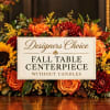Fall table centerpiece with orange and red flowers and a sign